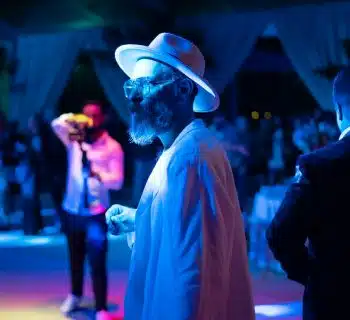 a man in a white hat and sunglasses standing in front of a group of people