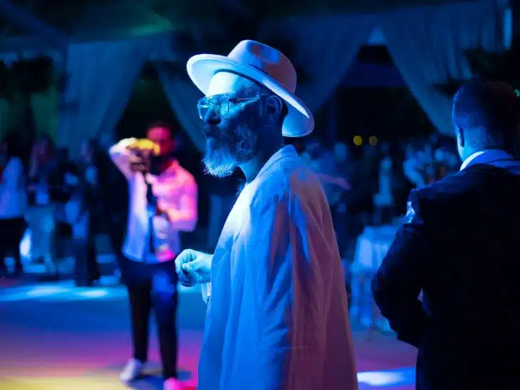 a man in a white hat and sunglasses standing in front of a group of people