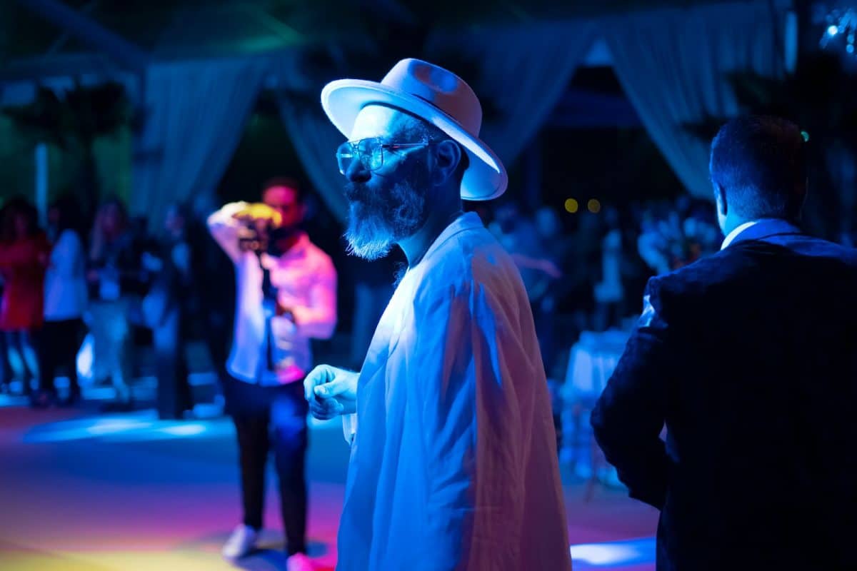 a man in a white hat and sunglasses standing in front of a group of people