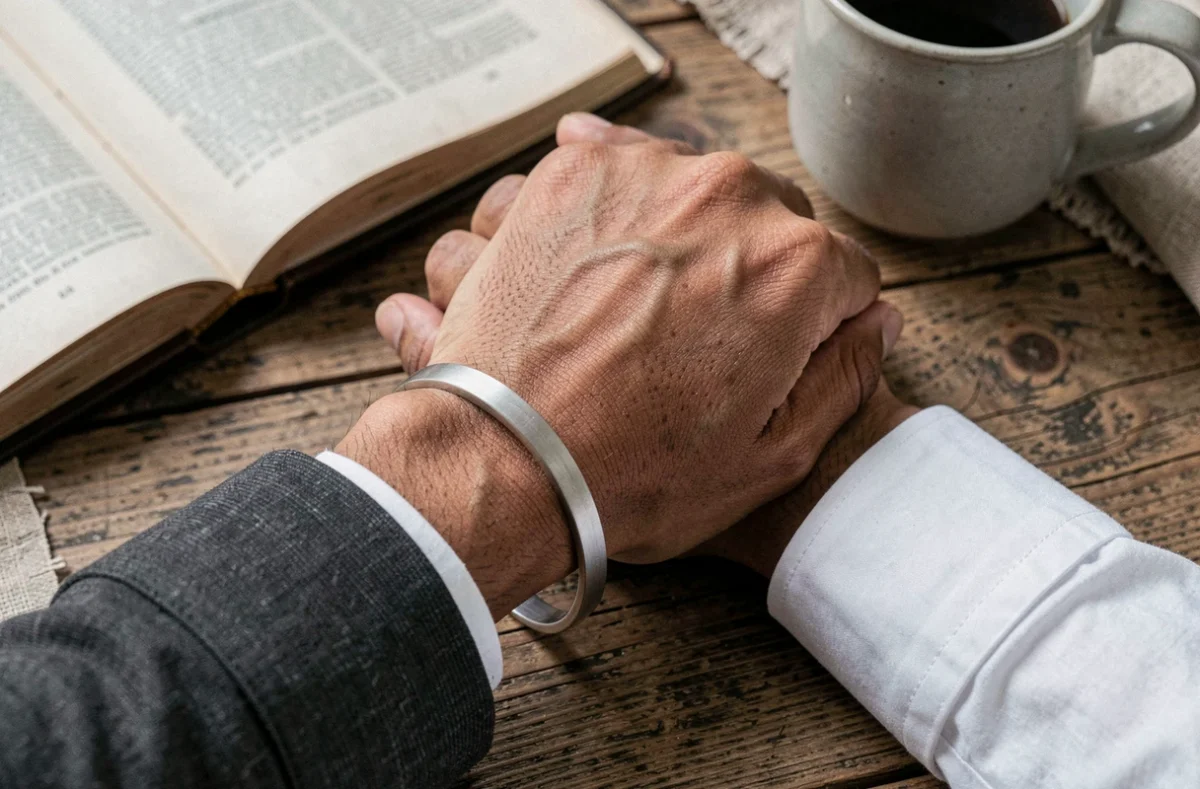 Gros plan de deux poignets portant des bracelets en argent brossé minimalistes posés sur une table en chêne