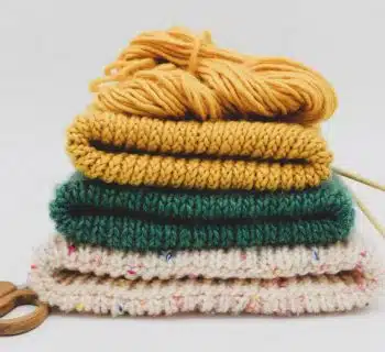 a stack of knitted sweaters and a pair of scissors