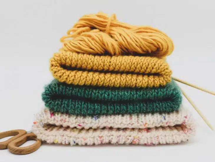 a stack of knitted sweaters and a pair of scissors